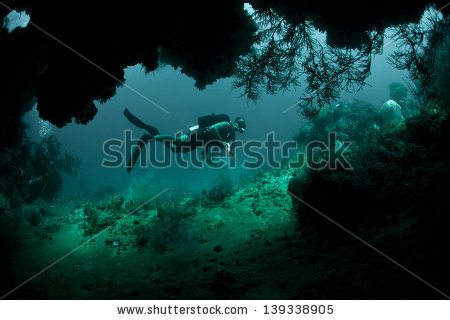 stock-photo-a-diver-explores-the-mouth-of-a-deep-cave-in-raja-ampat-indonesia-this-area-is-known-for-its-139338905.jpg